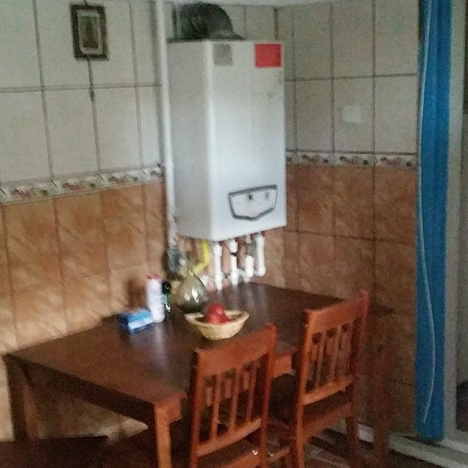 Bucataria casei cu masa de lemn si centrala pe perete